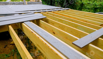 A new wooden, timber deck being constructed. it is on the decking. New deck patio