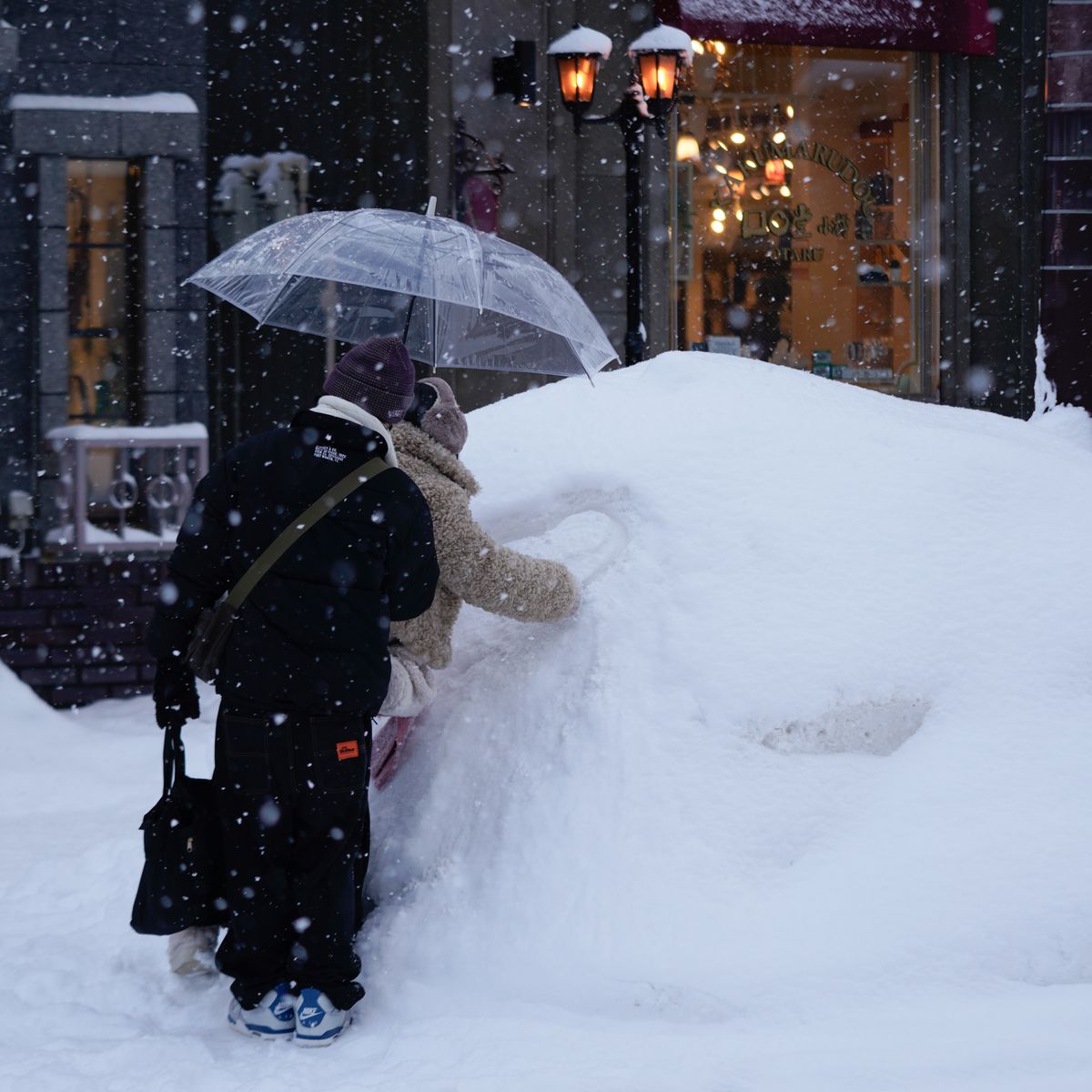 Couple sous un parapluie pendant une chute de neige en ville, illustrant les conditions hivernales rigoureuses