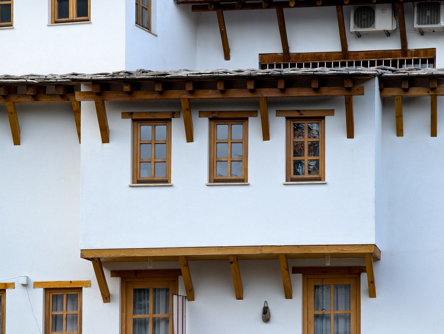 Gros plan de fenêtres en bois sur une façade blanche, support pour expliquer les coefficients thermiques Uw, Ug et Sw