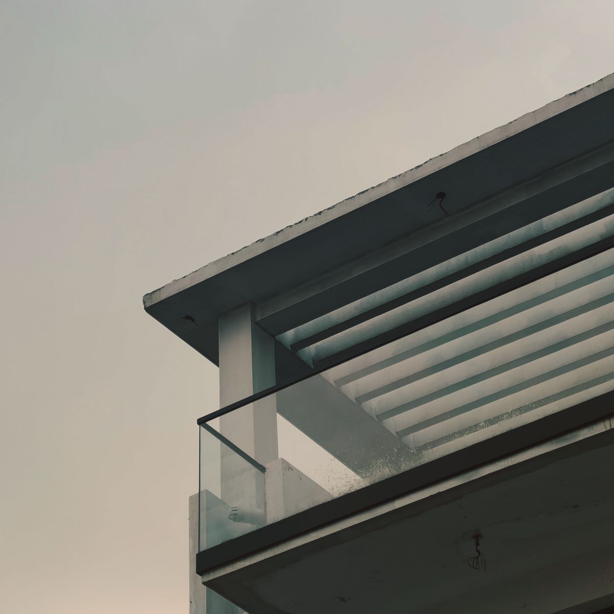 Coin de bâtiment moderne avec balustrade en verre et structure aux lignes géométriques épurées