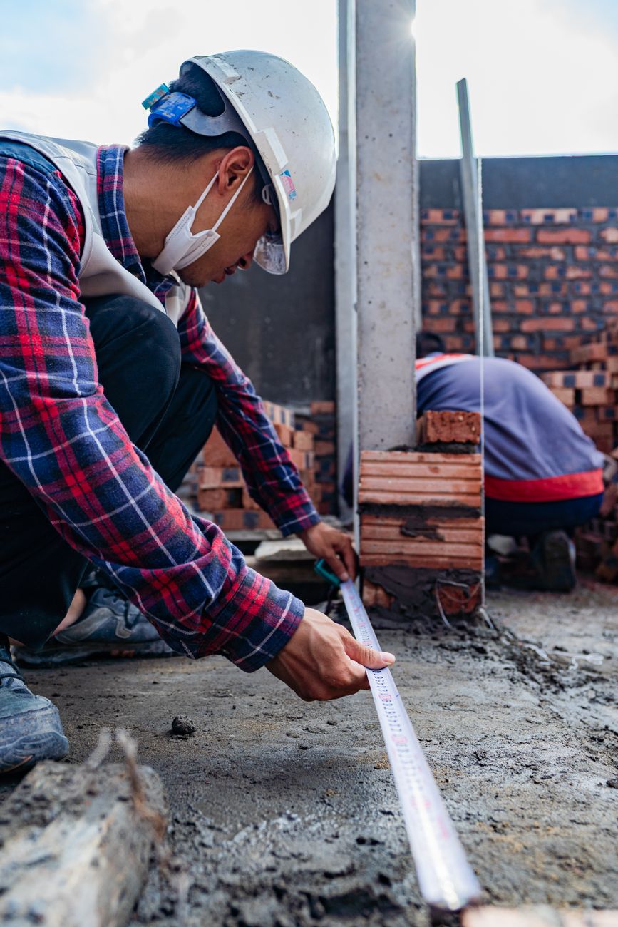 Ouvrier prenant des mesures au ruban sur un chantier, illustrant le relevé pour une pergola sur mesure dans le Haut-Doubs