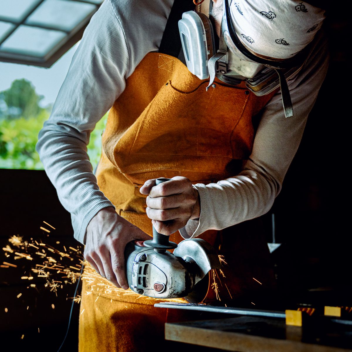 Artisan menuisier façonnant une pièce de bois à l'outil électrique dans son atelier ensoleillé