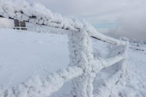 Terrasse et clôture extérieures recouvertes de neige et de gel en hiver, illustrant les contraintes du froid sur les matériaux