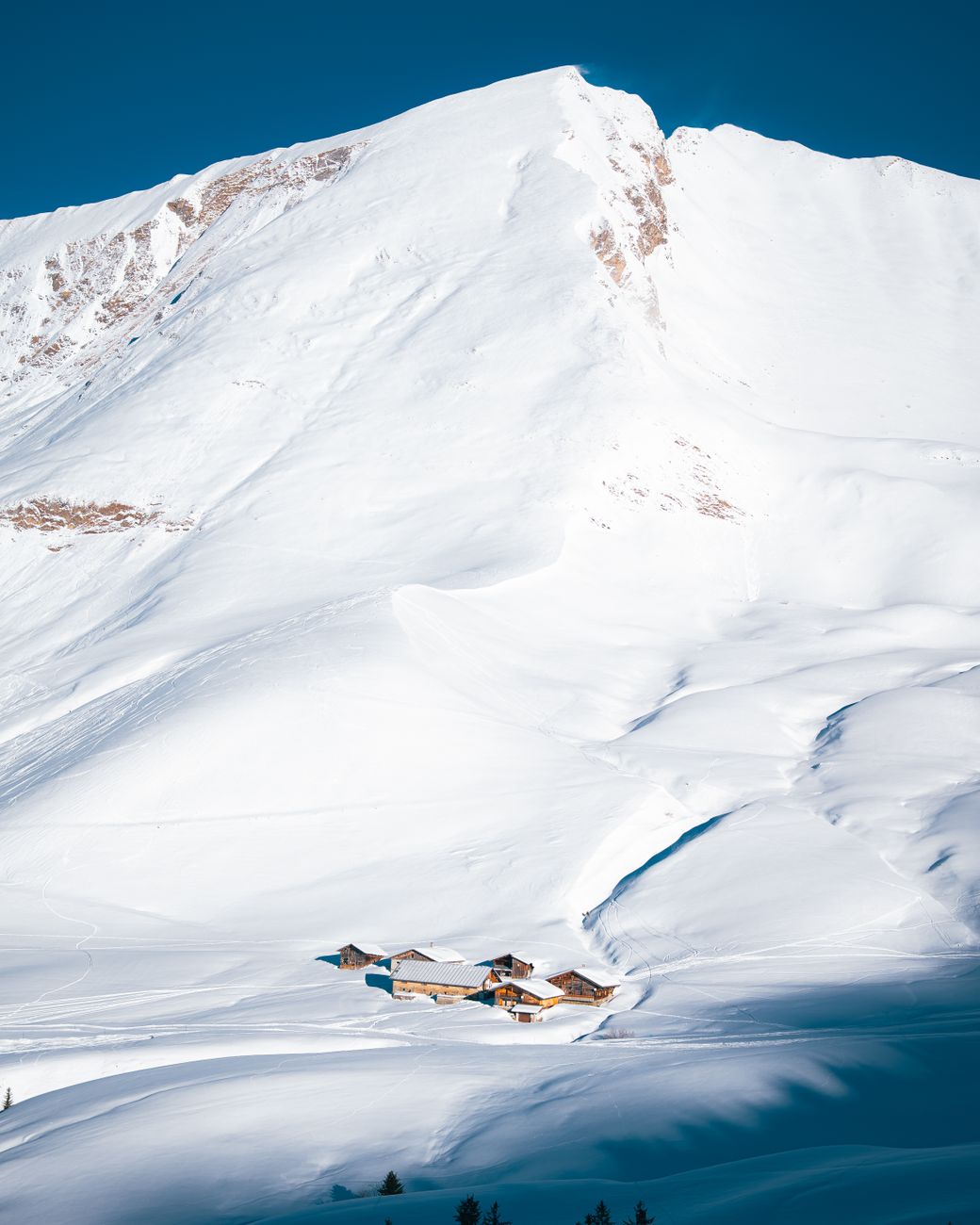 Chalet alpin niché dans les montagnes enneigées du Grand-Bornand, illustrant le remplacement de fenêtres en zone froide