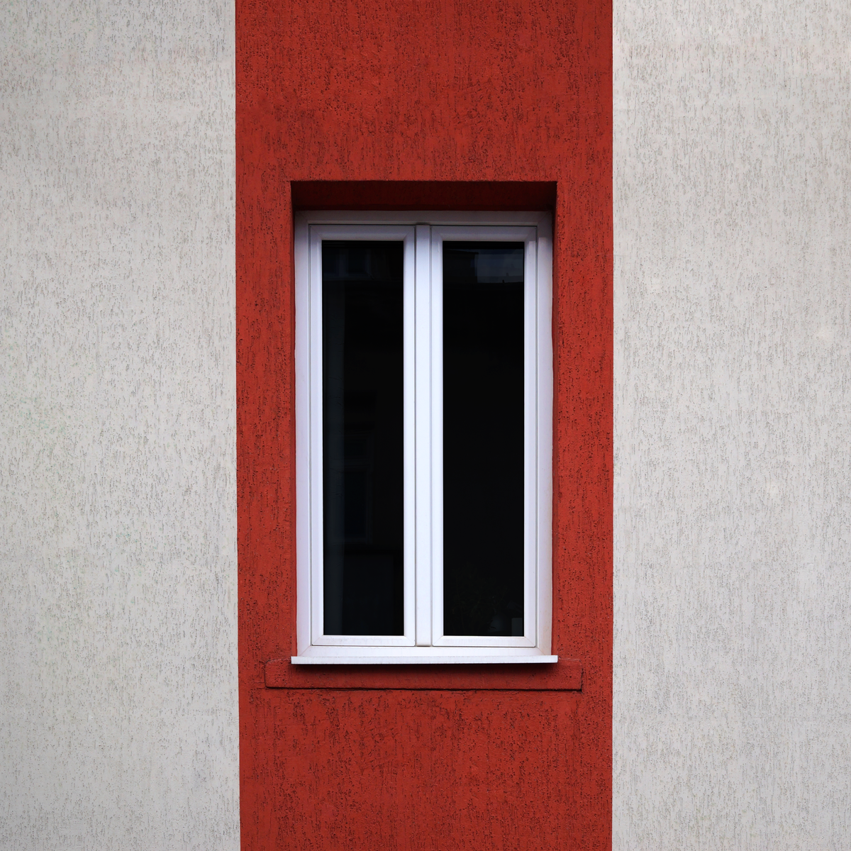Fenêtre moderne sur une architecture minimaliste contrastée en rouge et blanc