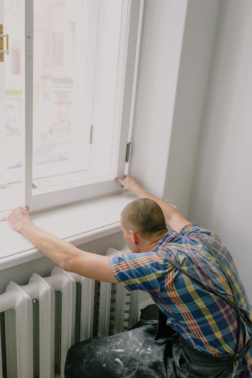 Artisan installant une fenêtre dans une maison neuve, main-d'oeuvre qui influence le prix selon la pose et le matériau