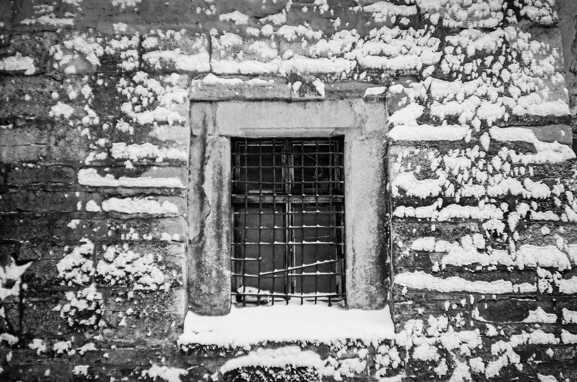 Vieille fenêtre en bois altérée sur un mur ancien, illustrant les contraintes du climat froid sur le bâti du Haut-Doubs